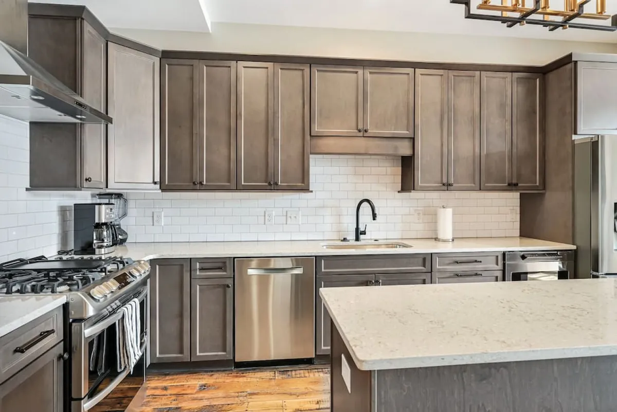A warm, welcoming kitchen scene centered on a kitchen island and surrounded by stainless steel appliances and cabinetry. The setting is ideal for preparing meals, hosting gatherings, or enjoying family time, spotlighting the kitchen as the heart of the home.