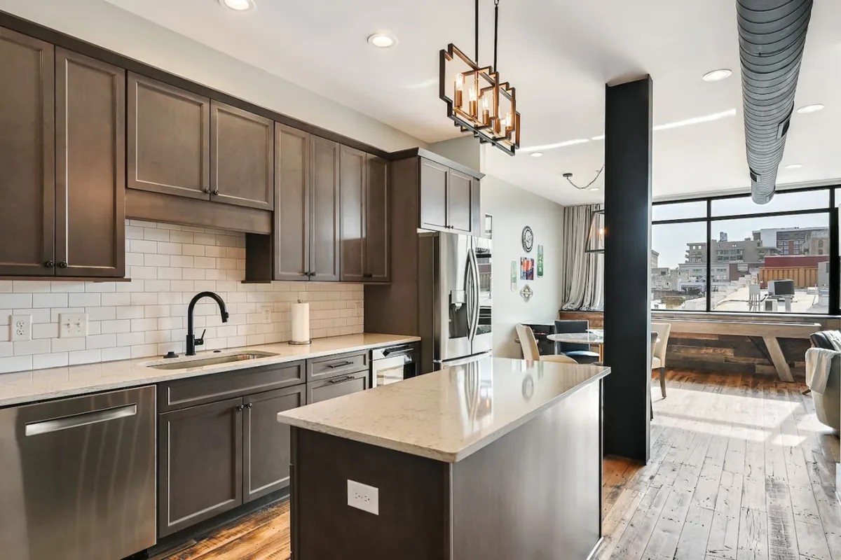 An inviting kitchen with modern cabinetry, granite countertops, and a bright open layout. Large windows invite natural light, and the kitchen seamlessly connects to adjacent living or dining spaces, emphasizing an open concept design.