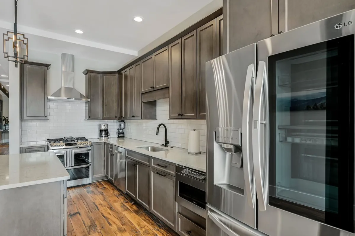 A modern kitchen featuring stainless steel appliances, a spacious kitchen island, and sleek cabinetry. Warm sunlight streams in, creating a welcoming atmosphere perfect for cooking or entertaining. The open layout allows for easy movement and socializing while preparing meals.
